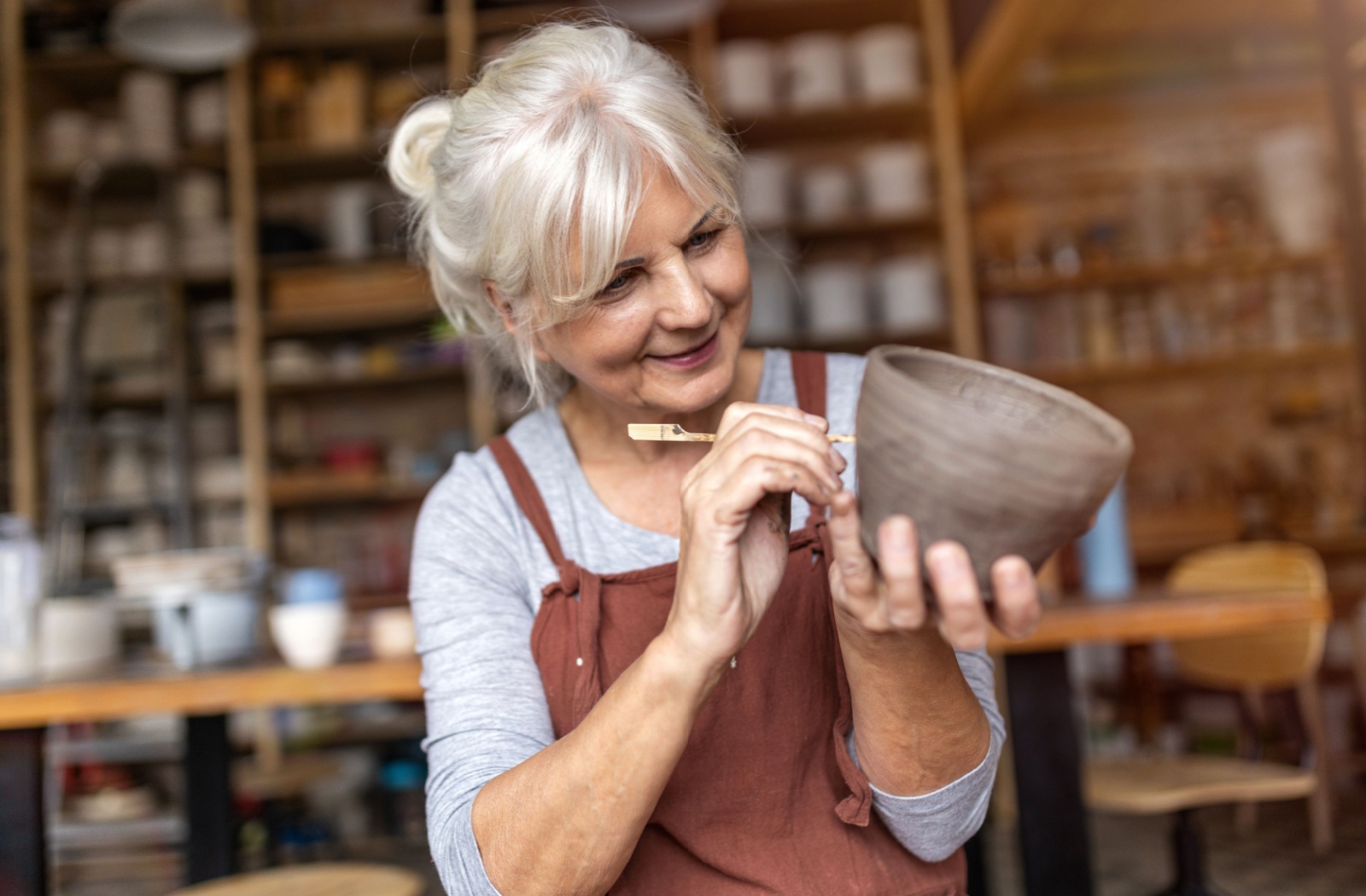 A happy senior engages in pottery making as a way of staying happy and satisfied in life.