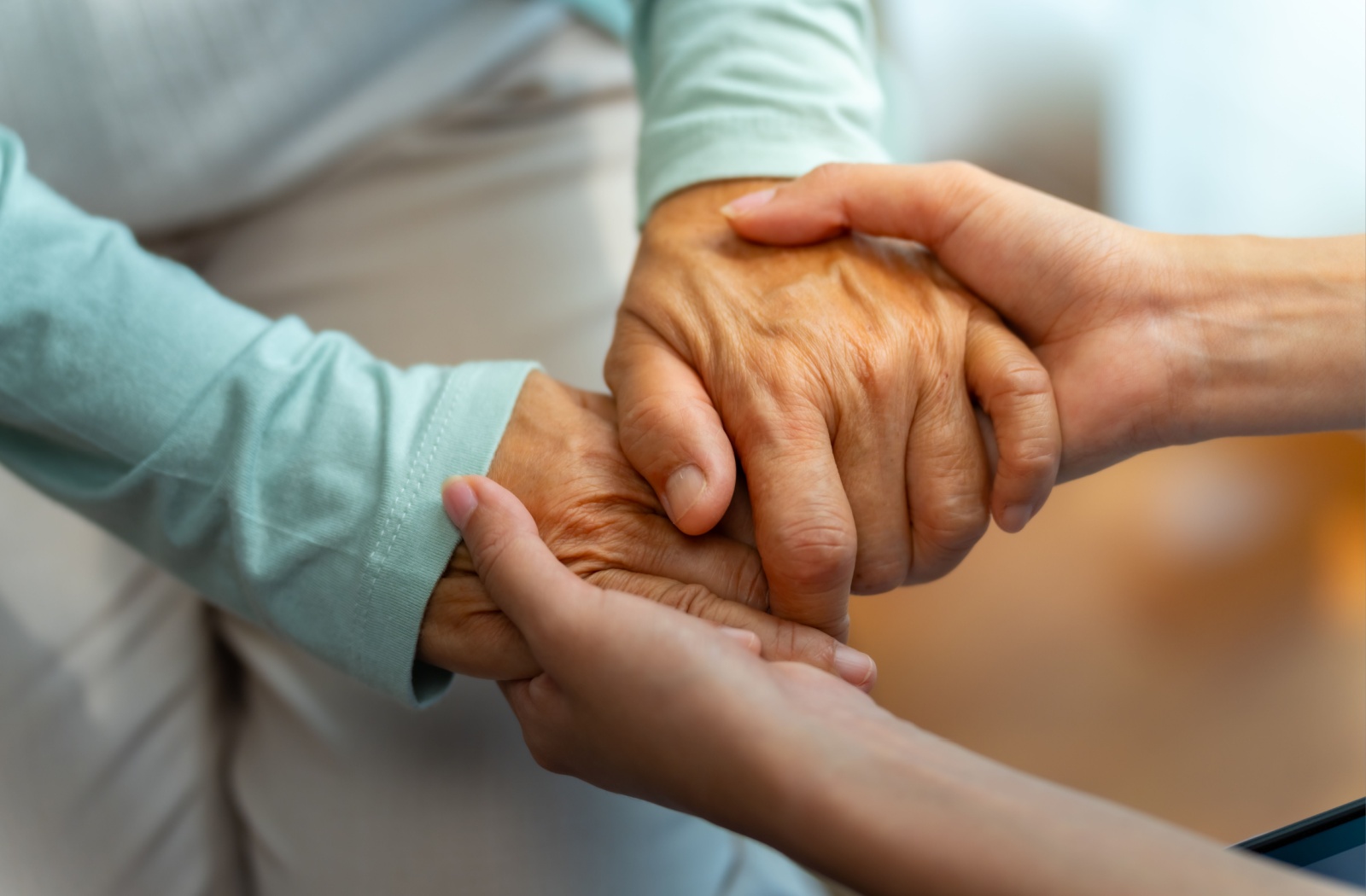 A close-up image of a caregiver holding a resident's hands in memory care.
