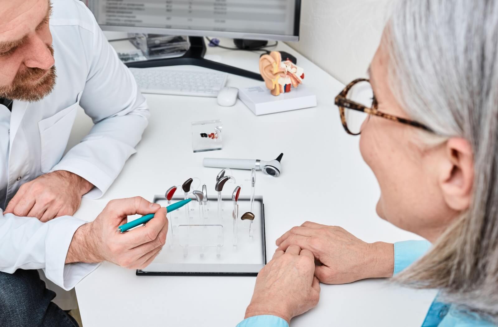 A senior consults with an audiologist to learn more about different types of hearing aids that could help them hear better