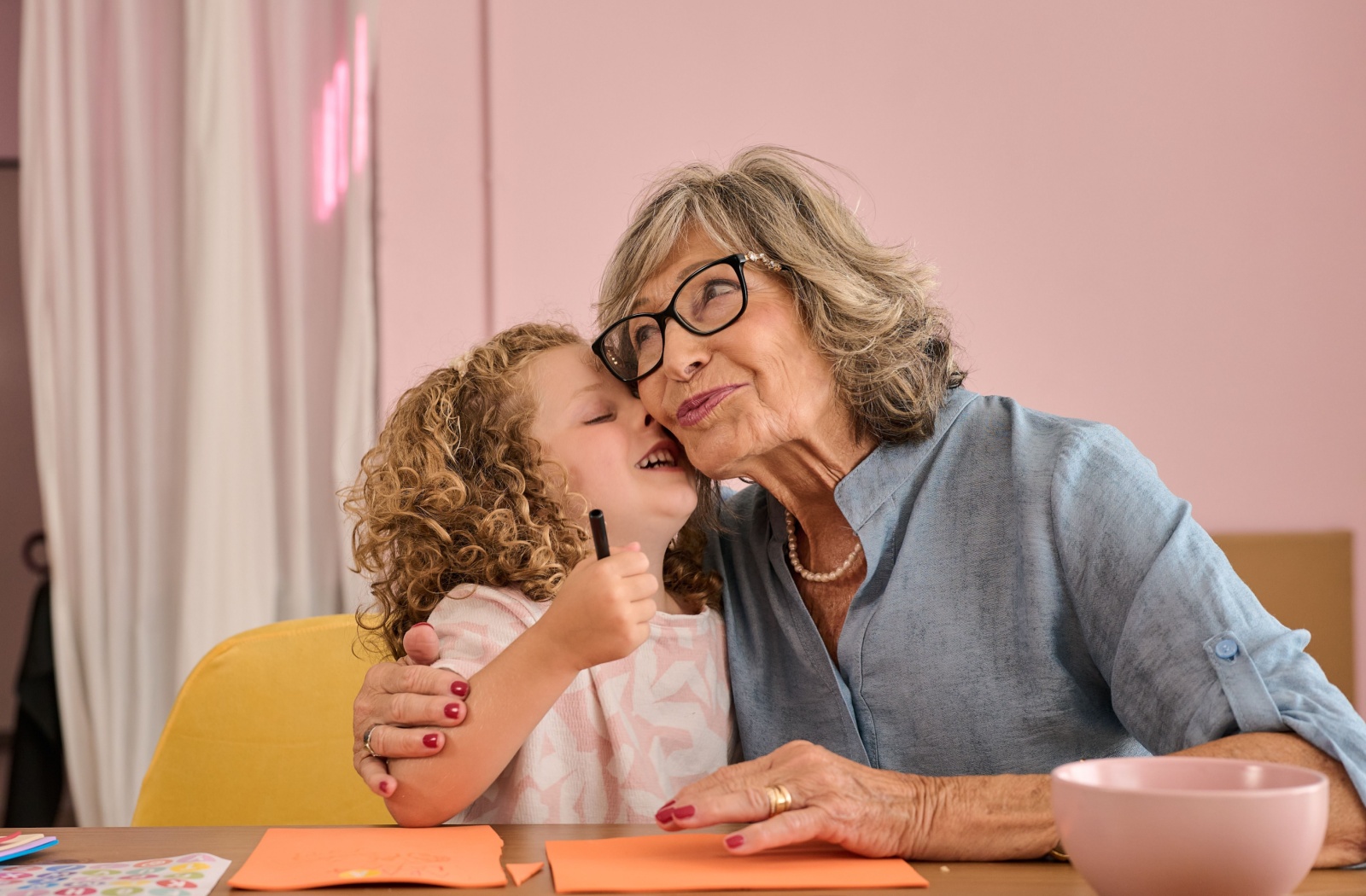 Senior sharing a hug with a child while making crafts at a table with paper and markers