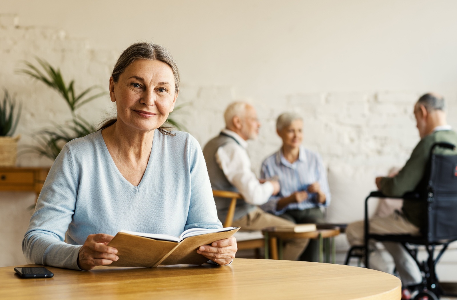 A senior woman with grey hair smiling while holding a book