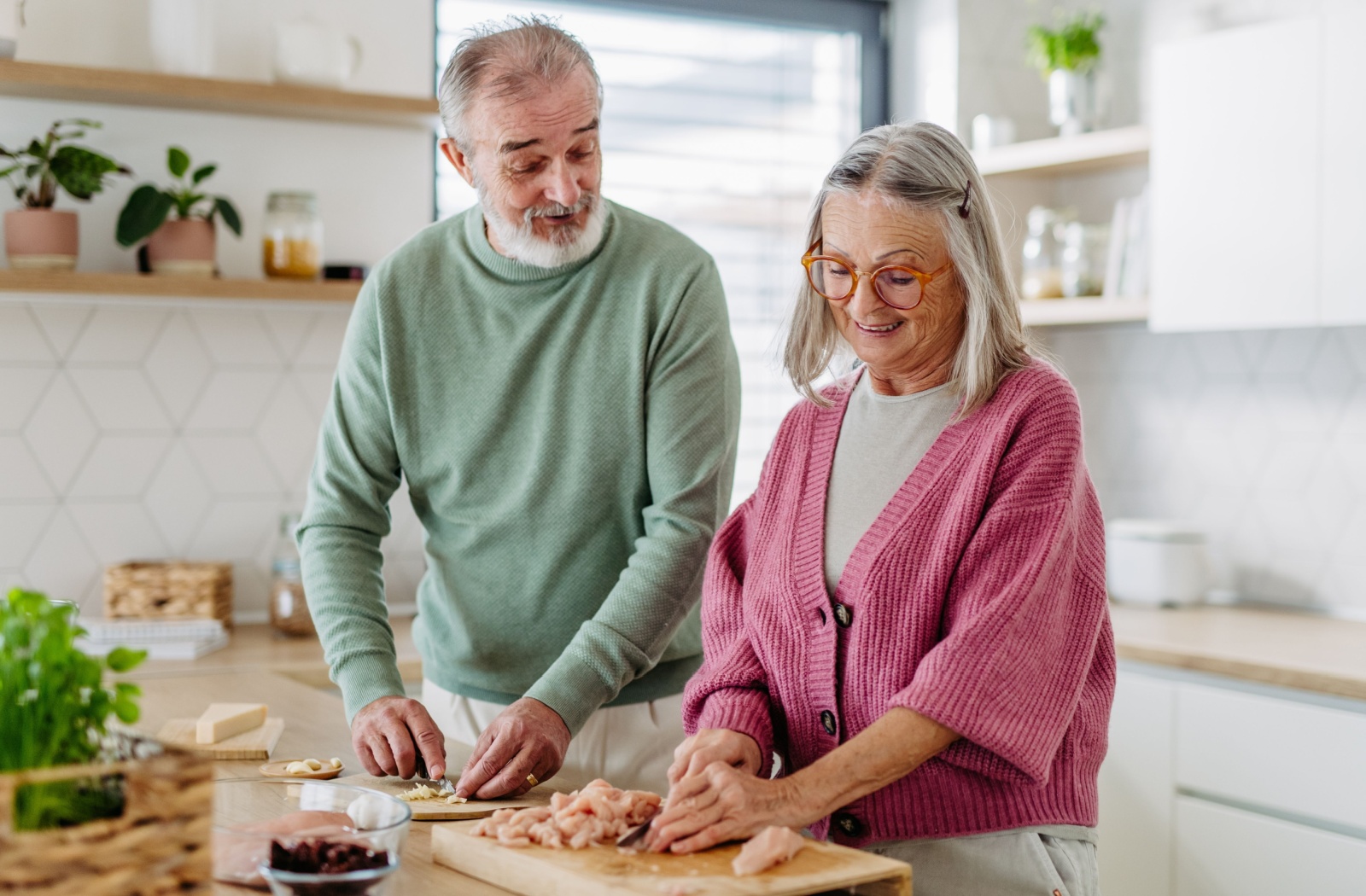 A happy couple prepares a high-protein meal with chicken together.