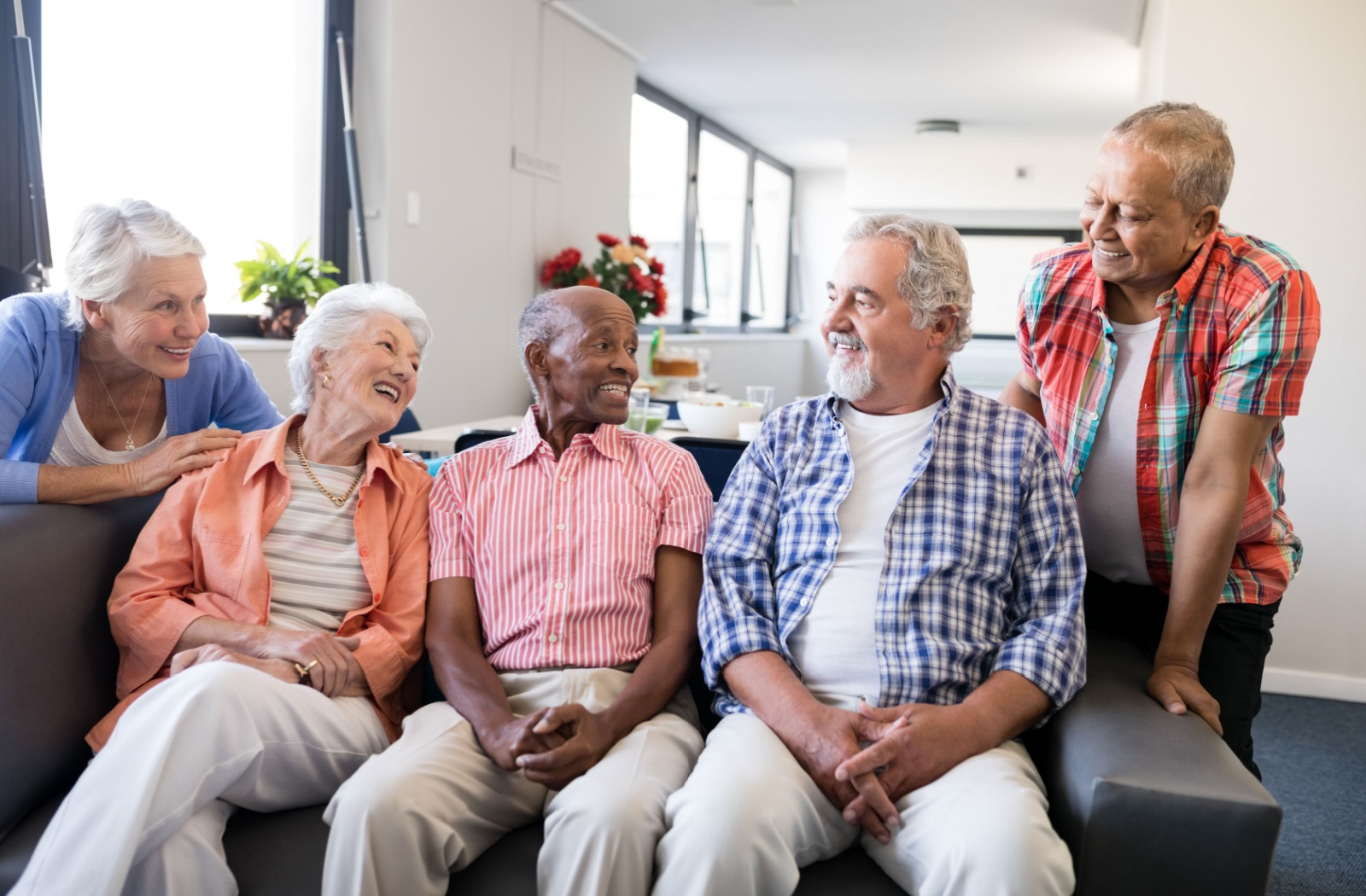 5 seniors smiling and laughing in a senior living community
