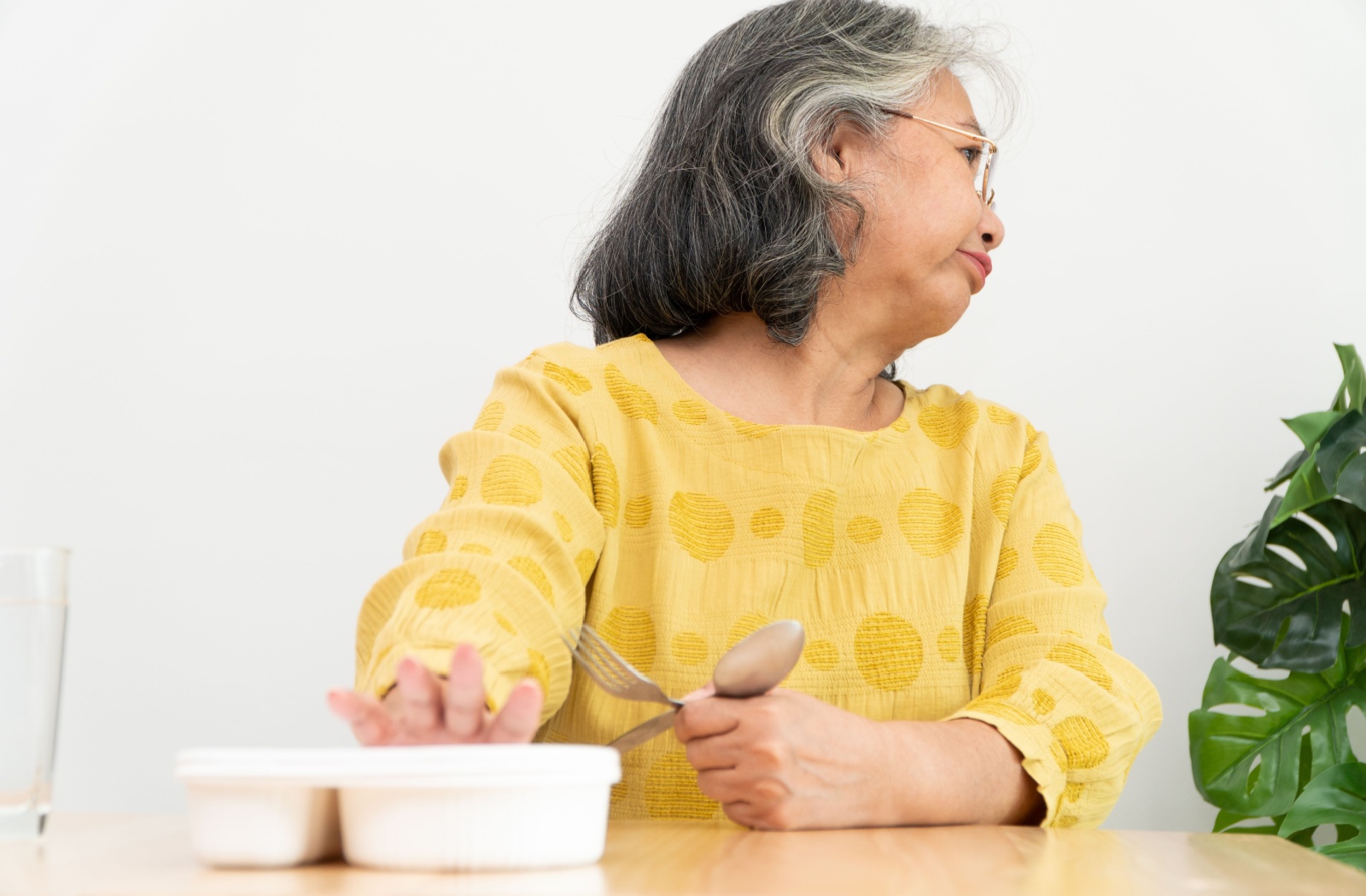 An older woman with no appetite pushing away her meal.