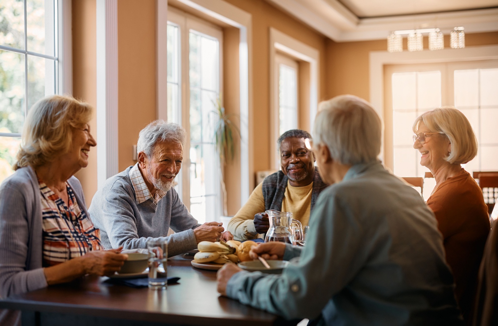 A group of seniors sitting around a table, eating and enjoying breakfast together.