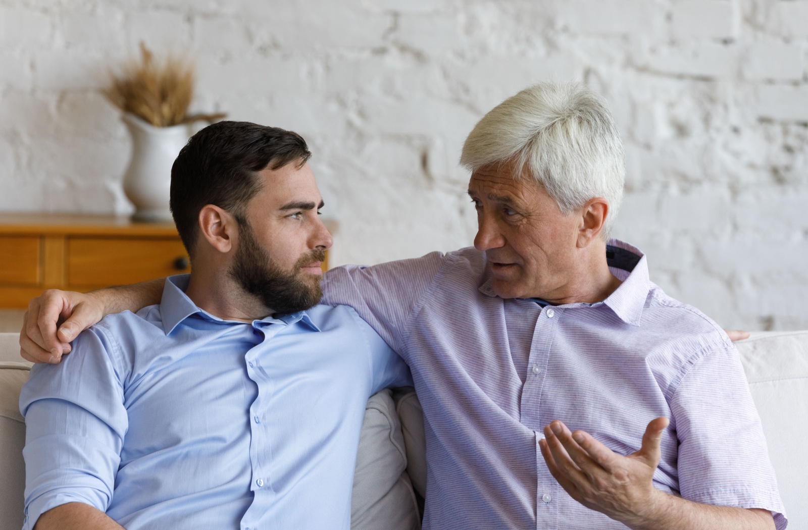 An adult child makes eye contact with their senior parent while talking to maintain a good line of communication.