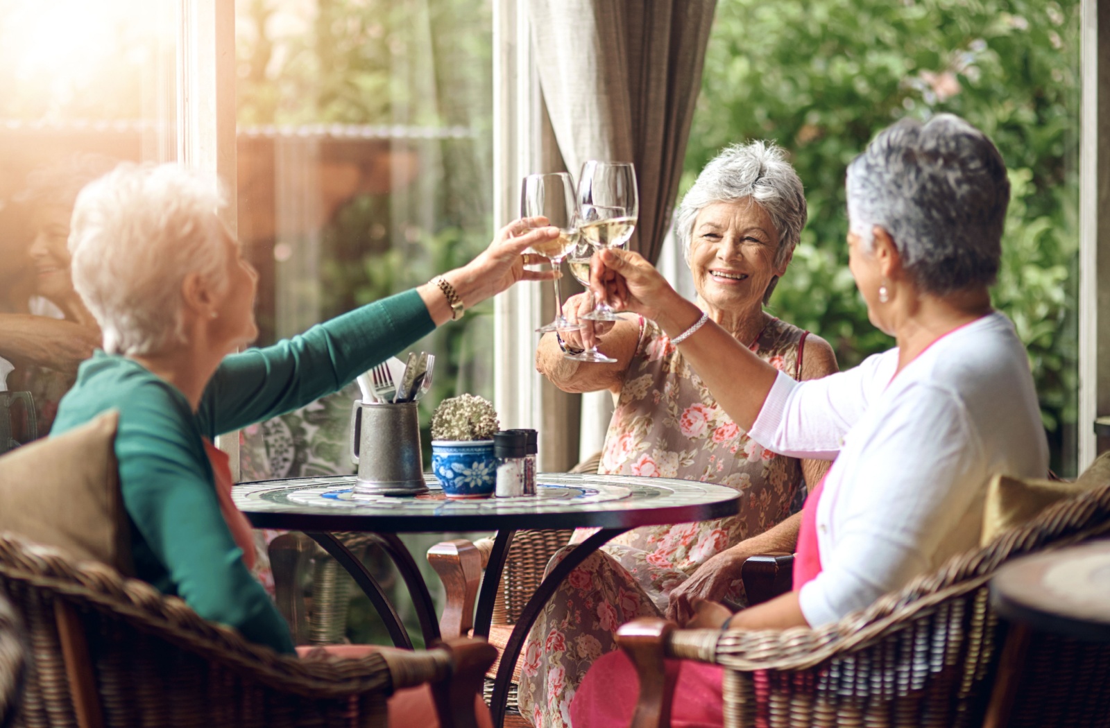 A group of seniors enjoy each other's company over a glass of wine.